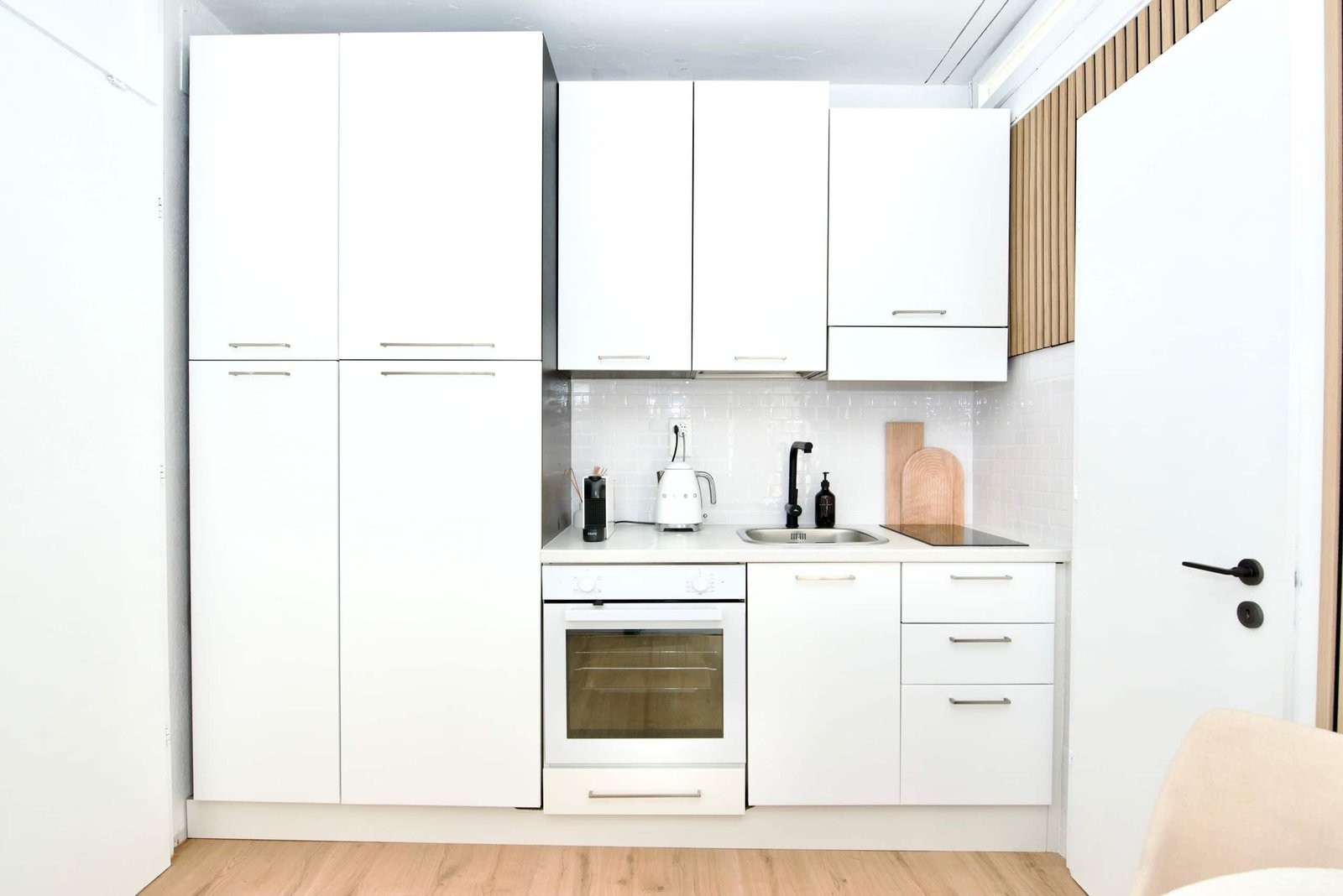 A full kitchen behind the white doors: oven, hob, fridge, all of it.